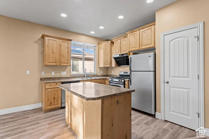 Kitchen featuring natural wood cabinetry, central island with stone-finish countertop, recessed lighting, and wood-finish flooring