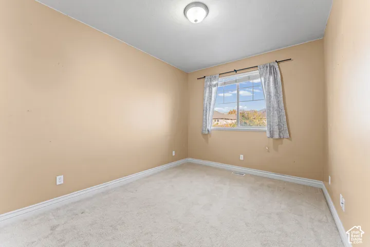 Neutral-toned bedroom featuring carpeting, a flush-mount ceiling light fixture, and a window with exterior scenery