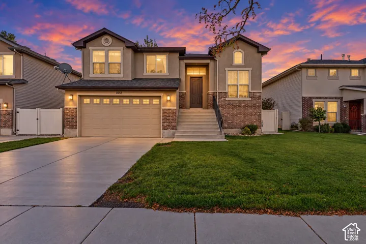 Two-story exterior featuring a mix of stucco and brick siding, an attached two-car garage, and concrete driveway