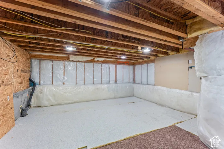 Unfinished lower level featuring exposed wood joist ceilings, plastic vapor barrier wall insulation, and concrete flooring