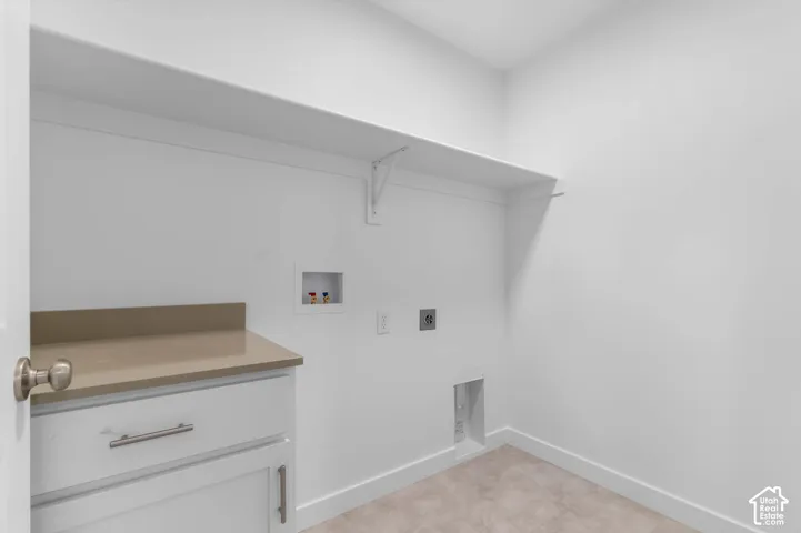 Utility space featuring built-in white cabinetry, solid surface countertop, overhead shelving, and wall-mounted laundry hookups