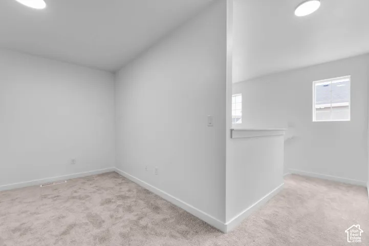 Neutral interior space featuring wall-to-wall carpeting, recessed ceiling lighting, and a partial partition wall with a flat cap