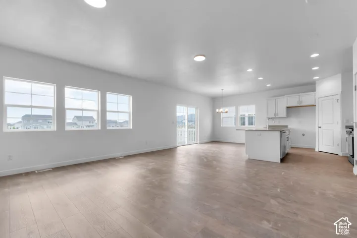 Open-concept interior featuring wood-finish flooring, recessed lighting, white cabinetry, a center island, and large-pane windows
