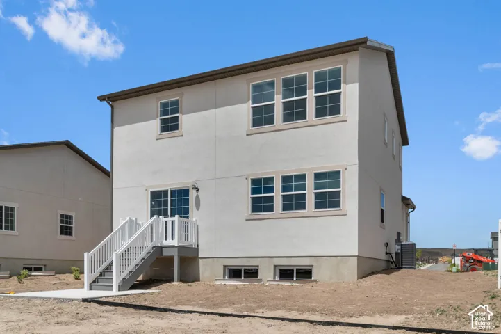 Two-story stucco exterior featuring a sliding glass door, white railing staircase, large dual-pane windows, and concrete patio