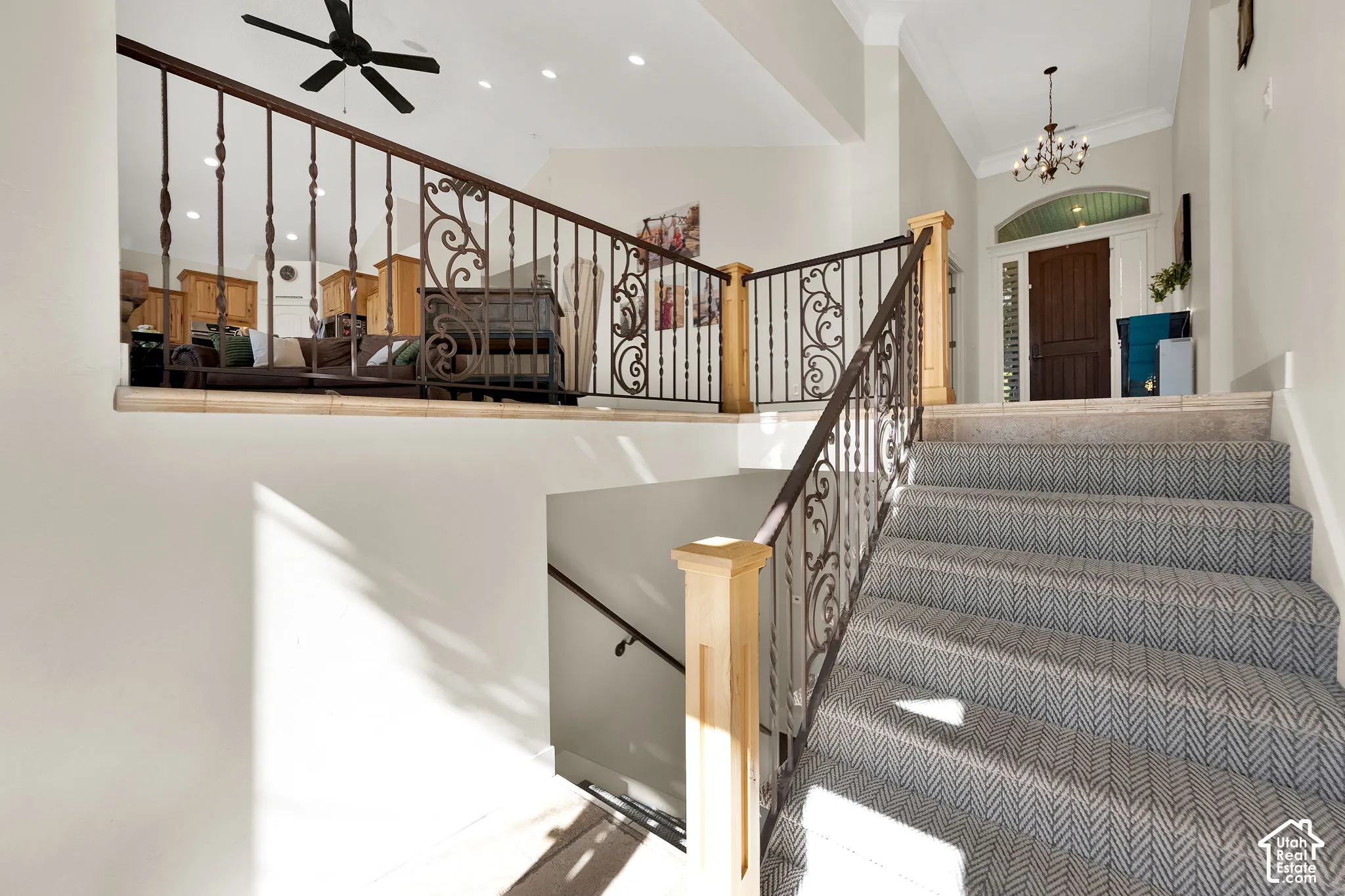 Foyer featuring custom decorative iron railings with wood-capped newel posts, recessed lighting, crown molding, and a traditional-style chandelier