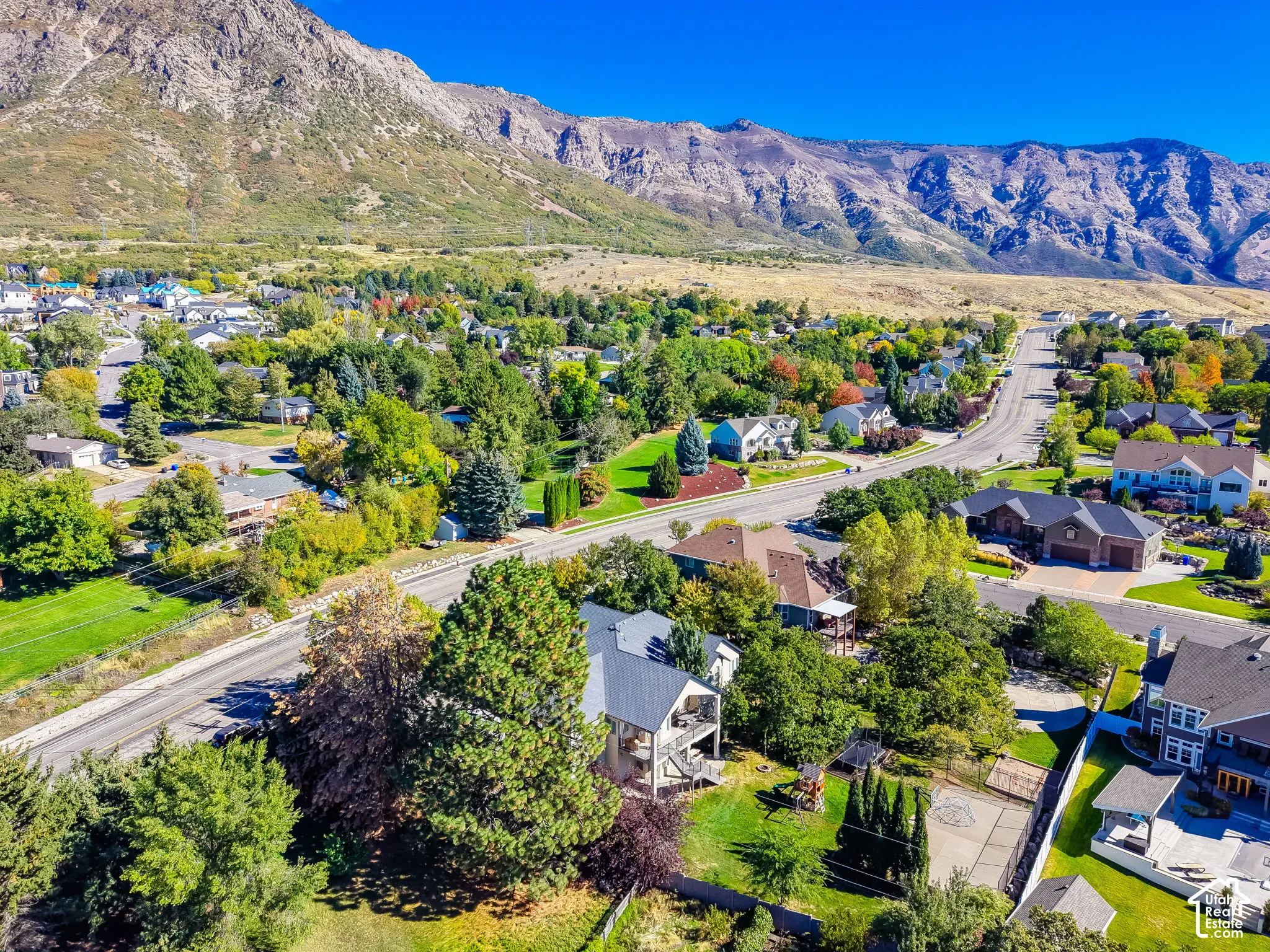 Aerial perspective featuring a residential lot with mature trees and expansive mountain terrain