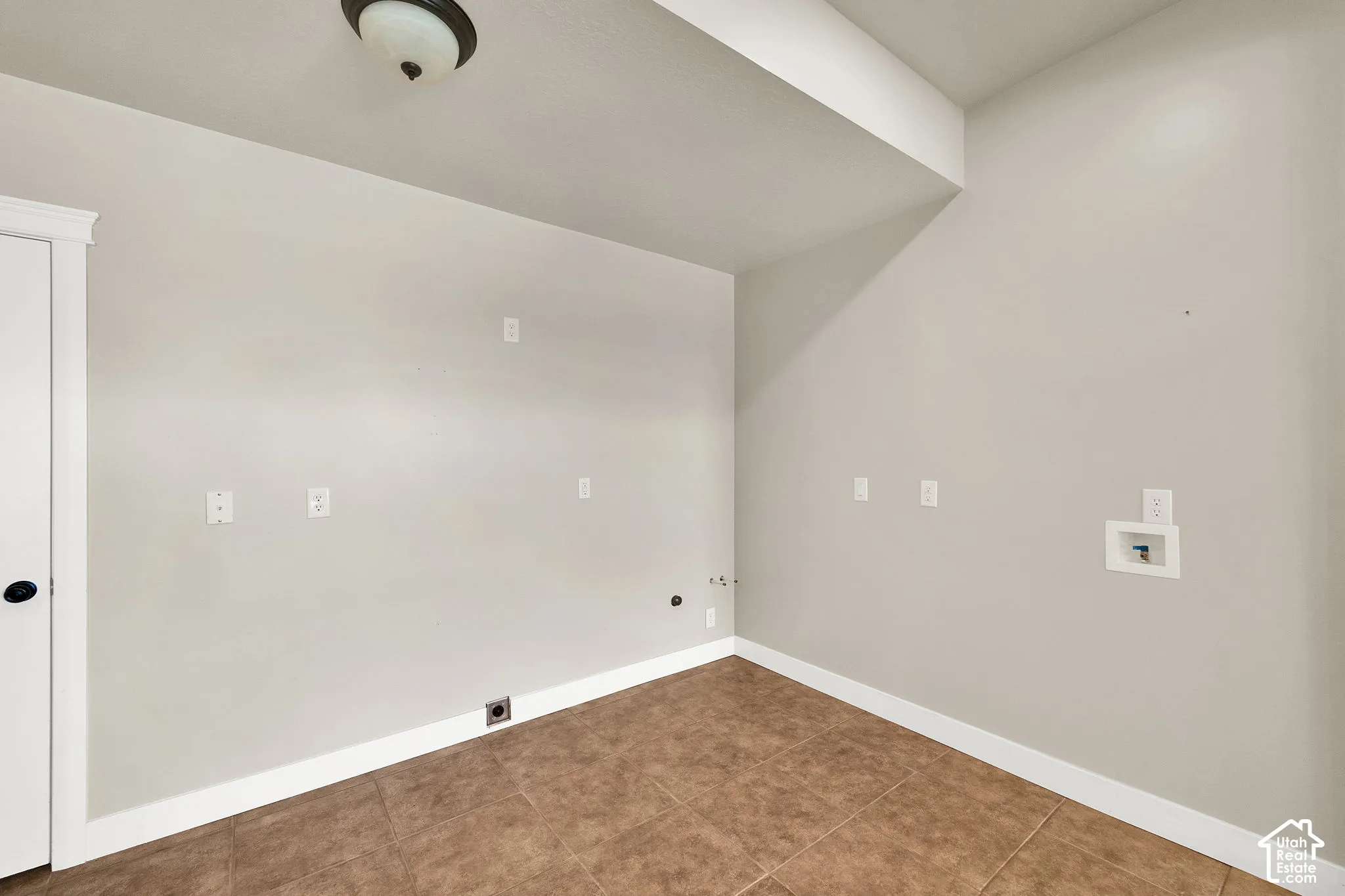 Utility space featuring neutral wall tones, tile flooring, an integrated recessed ceiling light fixture, and dedicated washer and dryer hookups