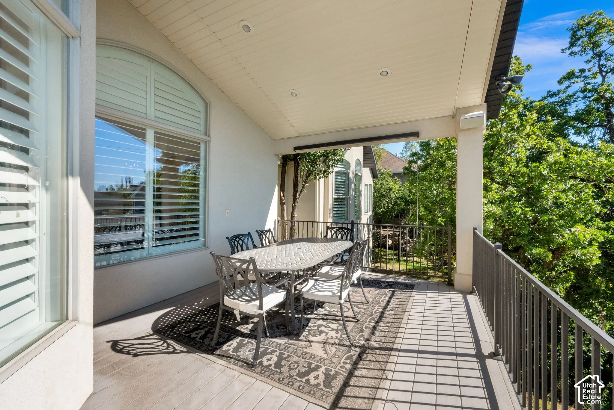 Covered deck featuring composite decking, recessed lighting, and metal railing