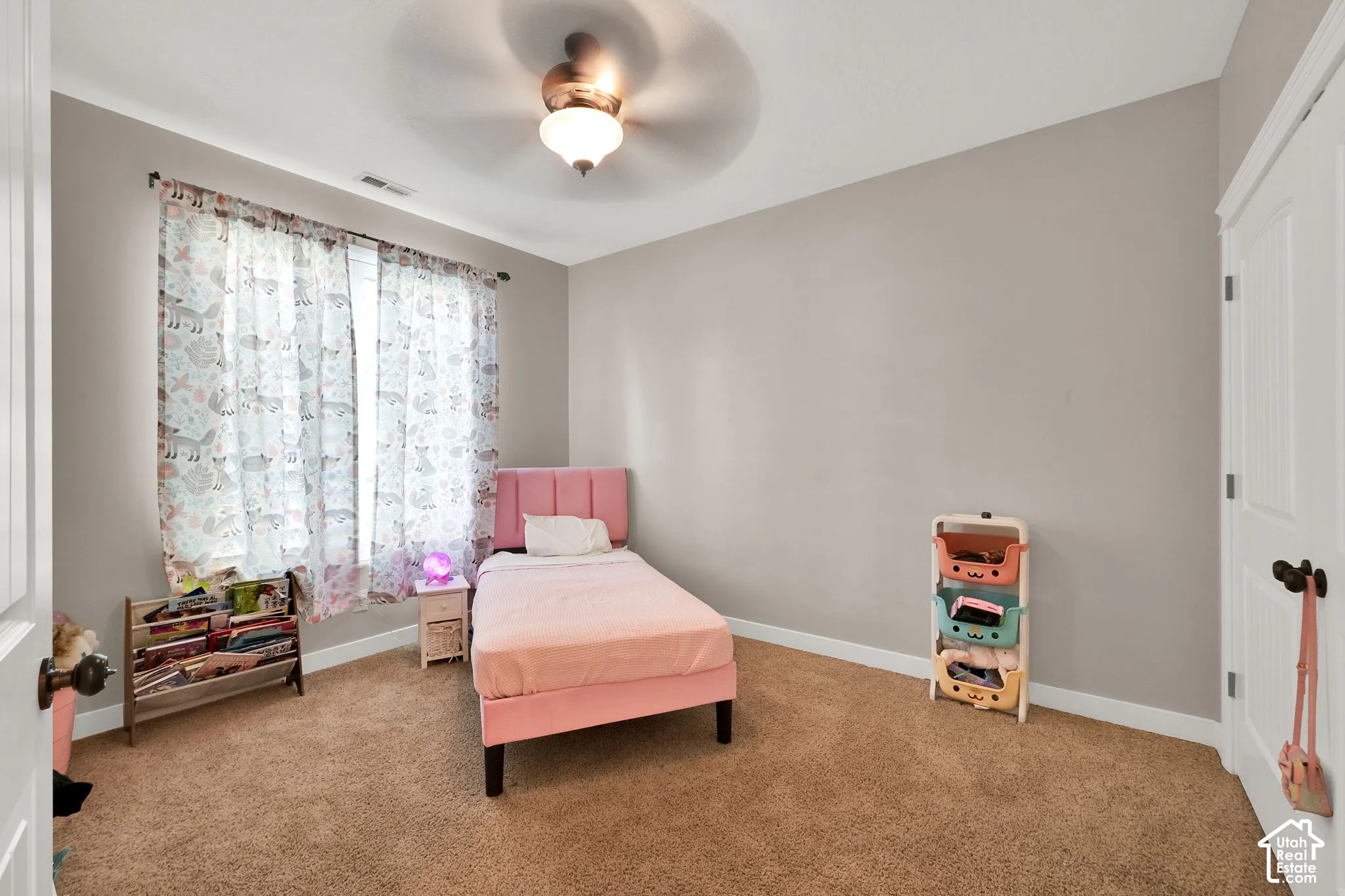 Neutral-toned interior room featuring carpeted flooring, a ceiling fan with integrated lighting, and a multi-panel door