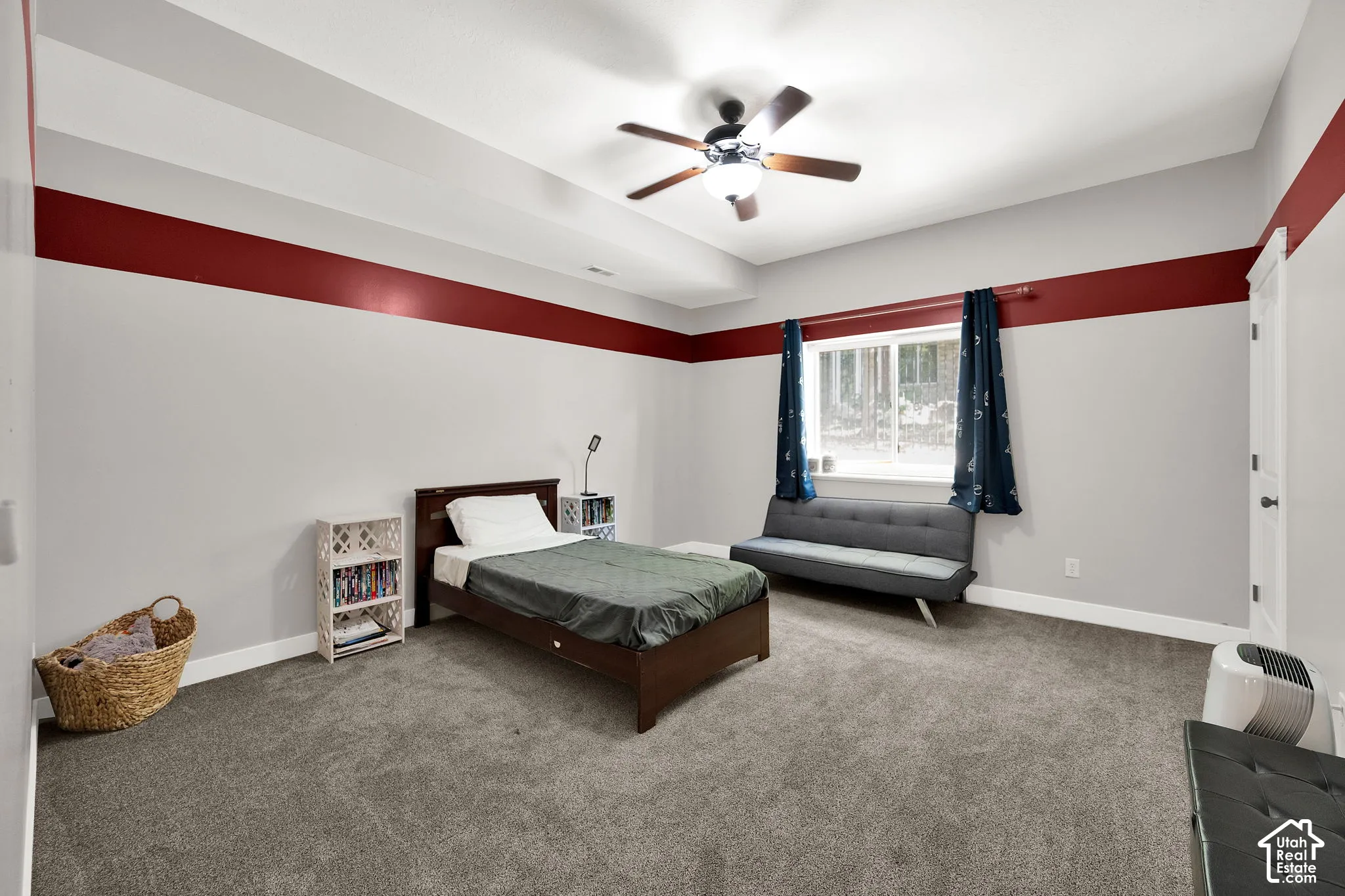 Tray ceiling featuring a central ceiling fan with integrated lighting, window with a sill, and neutral carpeting