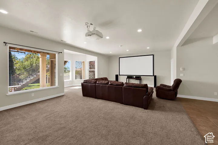 Recessed lighting, ceiling-mounted projector, wall-mounted projection screen, expansive windows, and carpeted flooring