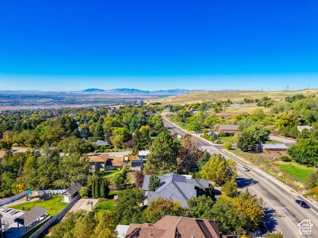 Aerial perspective of the property featuring a multi-pitched roof, manicured lawn, paved driveway, and expansive mountain range scenery