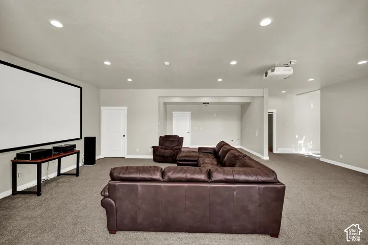 Large multipurpose room featuring neutral wall-to-wall carpeting, recessed ceiling lighting, a wall-mounted projection screen, and a ceiling-mounted projector