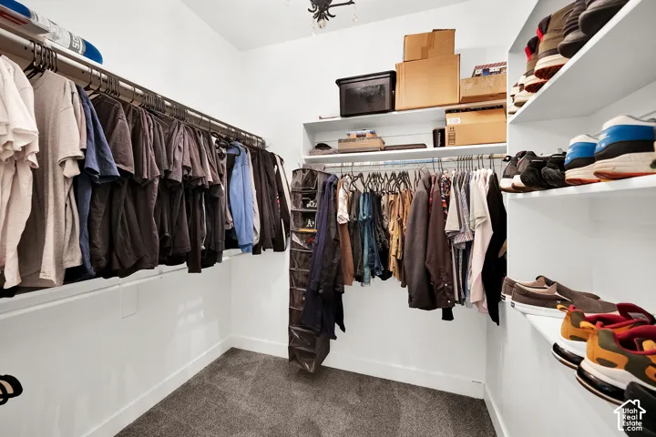 Walk-in closet featuring multi-level metal hanging rods and integrated white shelving
