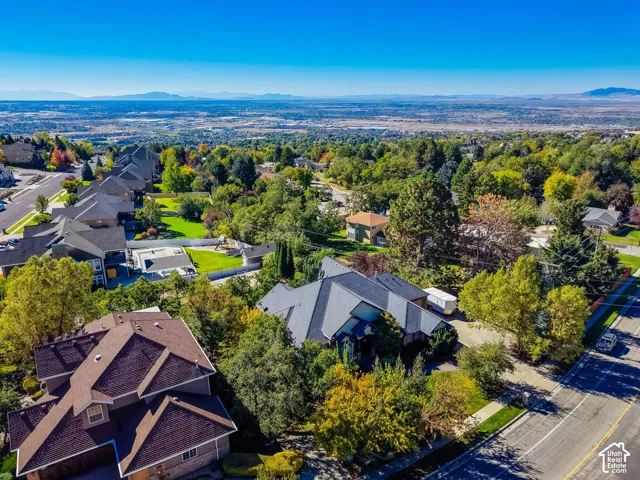 Aerial perspective of a multi-level residence featuring a multi-gabled roofline, mature landscaping, and an expansive mountain range backdrop