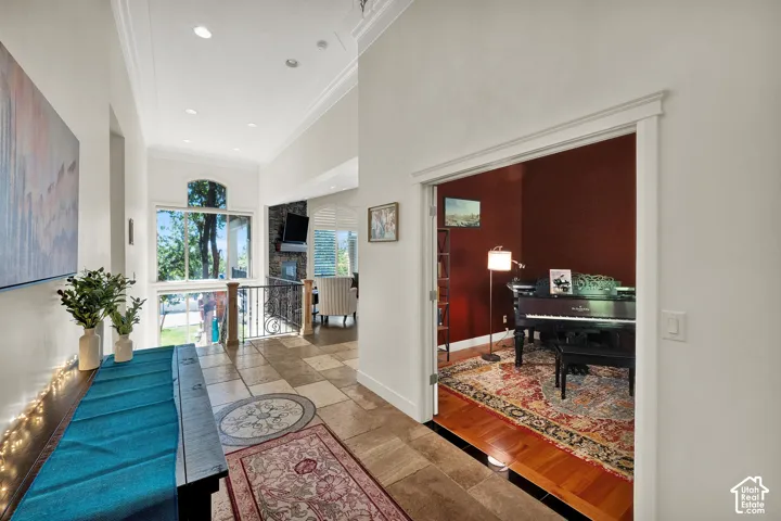 High-ceiling entryway featuring large-format stone tile flooring, recessed lighting, crown molding, and a dedicated room entry with double doors