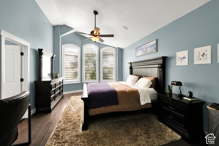 Vaulted ceiling featuring a central fan, arched windows with integrated blinds, and wood-finish flooring