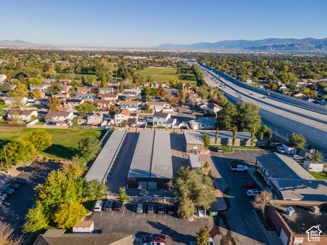 Aerial perspective of a multi-unit storage facility featuring paved parking areas, metal-roofed storage structures, and perimeter fencing