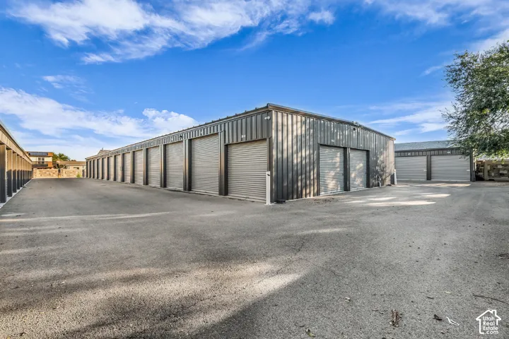 Multi-unit metal storage facility featuring steel roll-up doors, metal siding, a flat roof, and asphalt paving