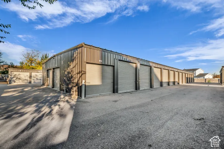 Commercial-grade metal exterior storage facility featuring multiple roll-up doors and asphalt paving
