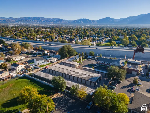 Aerial property perspective featuring multiple storage structures, paved parking areas, and surrounding mountain backdrop