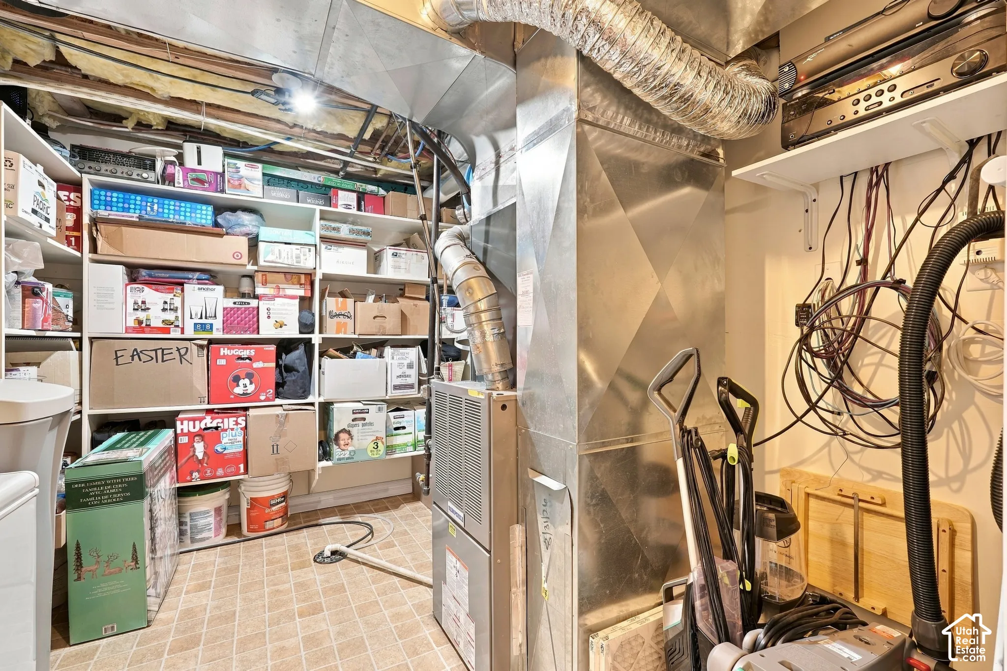 Utility area featuring built-in white shelving, metallic HVAC ductwork, and resilient vinyl tile flooring