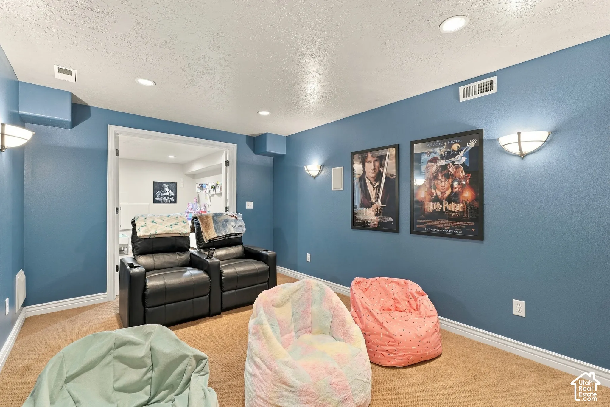 Interior space featuring neutral-toned carpeting, recessed ceiling lighting, and wall-mounted sconces