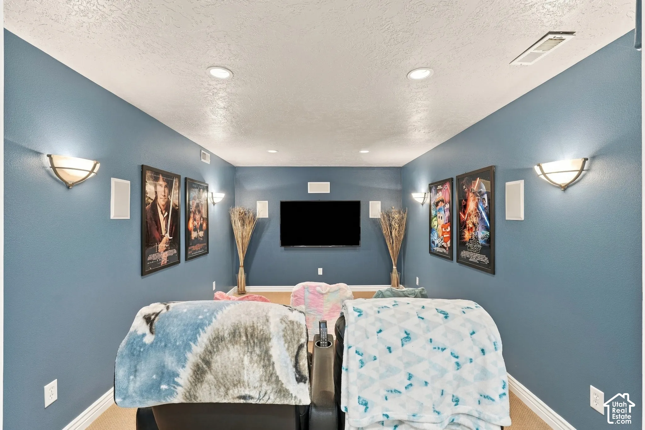 Media room featuring recessed lighting, wall-mounted light fixtures, built-in wall speakers, and a centrally mounted television display