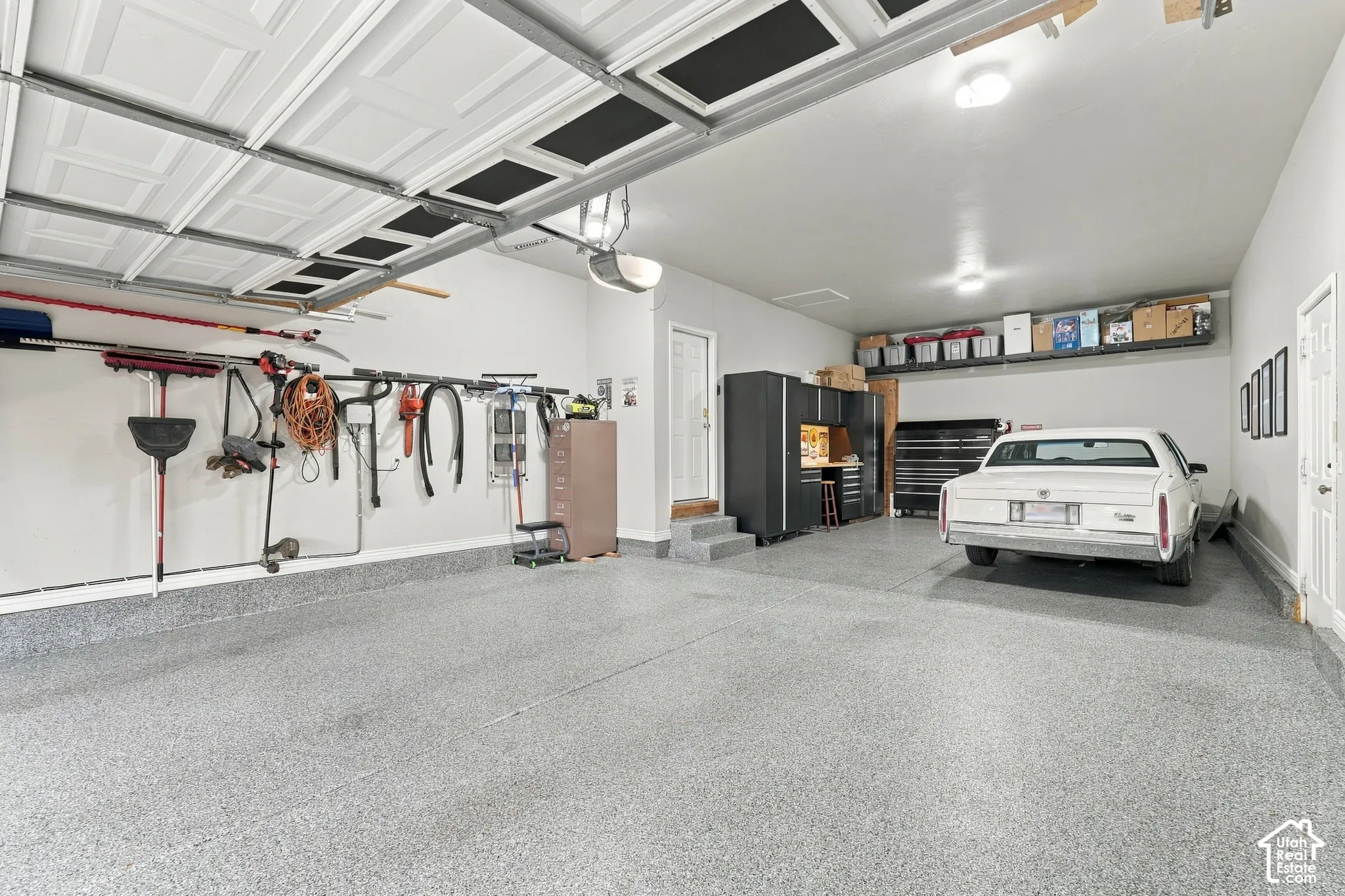 Multi-car garage featuring speckled epoxy flooring, built-in cabinetry, and integrated overhead storage shelving
