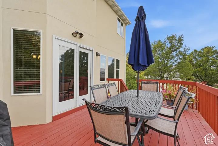 Elevated exterior deck featuring red-painted wood planks, matching wooden railings, and glass-paned double doors