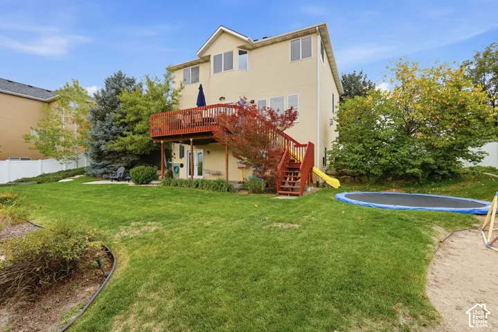 Rear exterior featuring a multi-level wood deck, an exterior staircase with railings, and a landscaped backyard with mature trees