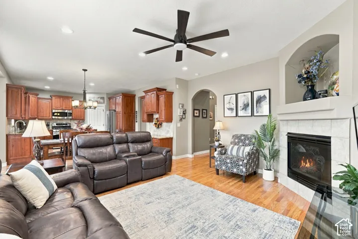 Open-concept interior featuring wood-finish flooring, a tile-surround fireplace with a built-in arched display niche, recessed lighting, and kitchen cabinetry with integrated appliances