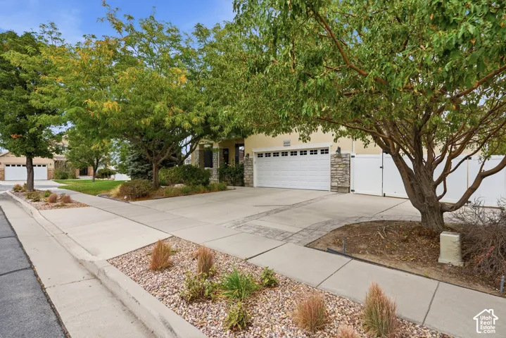Exterior featuring a multi-car garage, stone facade accents, concrete driveway, and xeriscaped front grounds