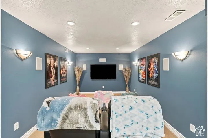 Media room featuring recessed lighting, wall-mounted light fixtures, built-in wall speakers, and a centrally mounted television display