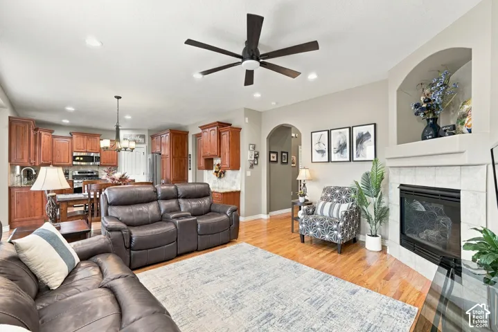 Open-concept floor plan featuring wood flooring, a fireplace with tiled surround and built-in arched alcove, recessed lighting, and wooden cabinetry