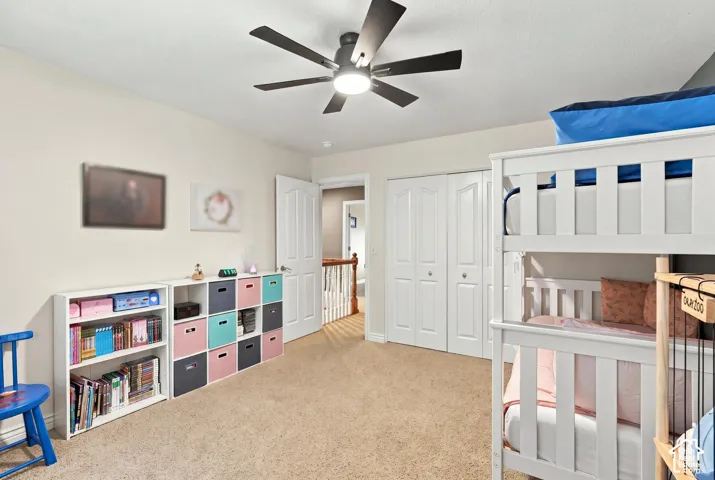 Bedroom featuring neutral wall paint, carpeted flooring, a ceiling fan with integrated lighting, and dual-panel closet doors