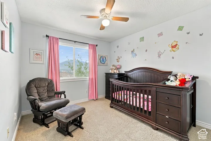Neutral wall palette featuring carpeting, a ceiling-mounted fan, and a horizontal window with mountain scenery