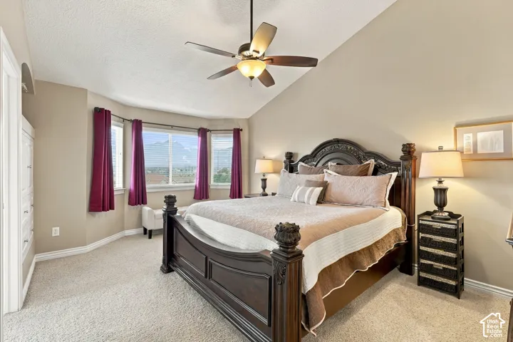 Vaulted ceiling featuring a central multi-blade ceiling fan with integrated lighting and a bay window configuration