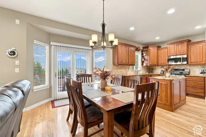 Kitchen featuring wood cabinetry, stone-tile backsplash, central island with stone countertop, stainless steel appliances, and wood-finish flooring