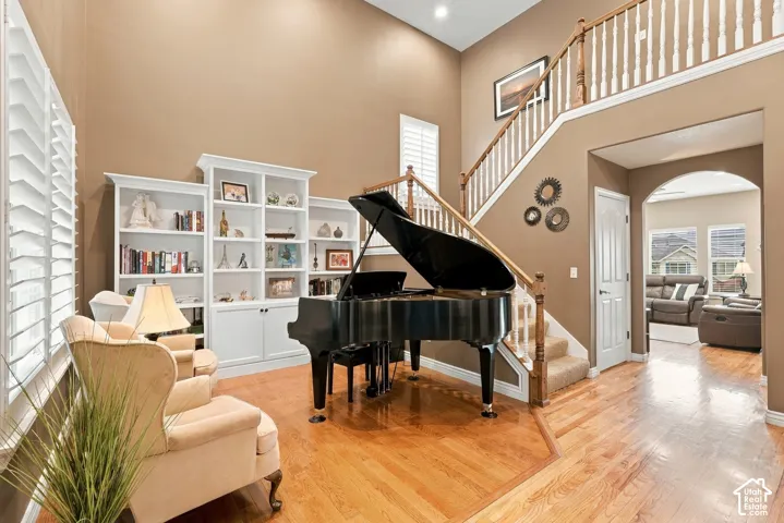 Two-story foyer with high ceilings, wood-finish flooring, built-in white cabinetry, and a staircase featuring wooden handrails and white balusters