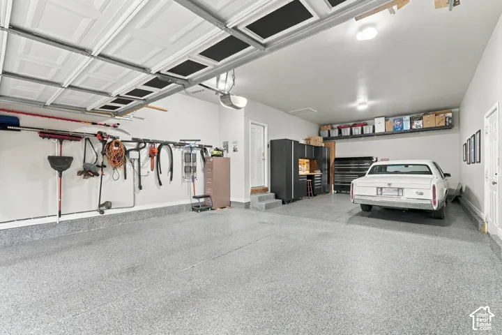 Multi-car garage featuring speckled epoxy flooring, built-in cabinetry, and integrated overhead storage shelving