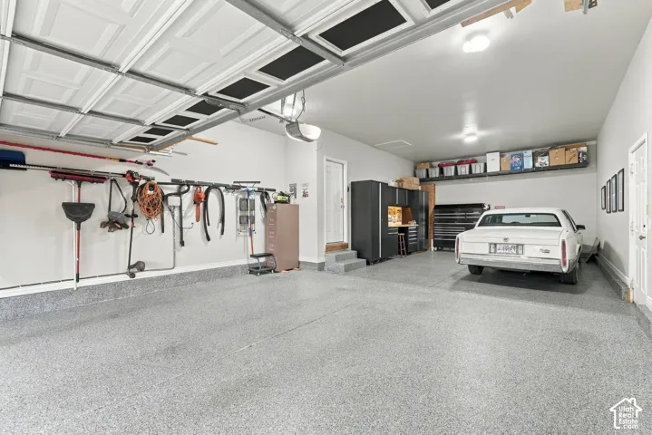 Garage featuring an epoxy-coated floor, built-in cabinetry, overhead storage shelving, and wall-mounted organization hardware
