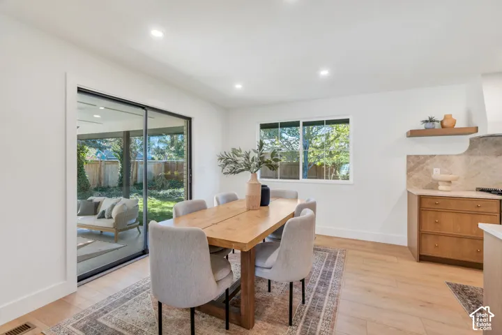 Wood-finish flooring, recessed lighting, sliding glass door, stone backsplash, and built-in wood shelving