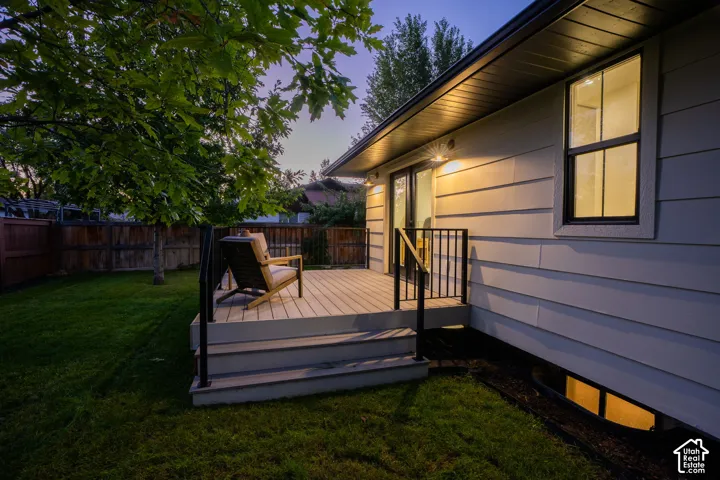 Raised exterior deck with black metal railing, horizontal lap siding, and attached exterior wall-mounted lighting