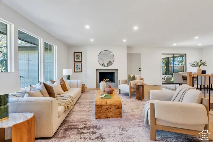 Living space featuring recessed lighting, large pane windows, and a central fireplace with stone-finish surround