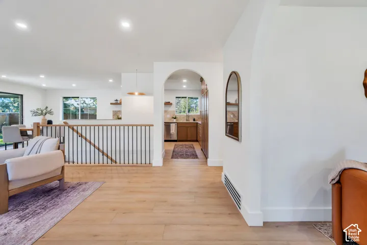 Interior space featuring wood-finish flooring, an arched entryway, recessed lighting, and a metal-spindle stair railing