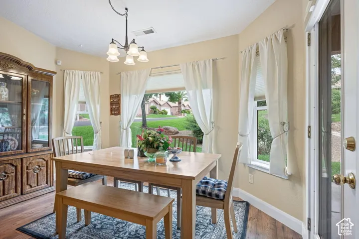 Bay window with expansive glass, wood-finish flooring, and a multi-arm metallic chandelier