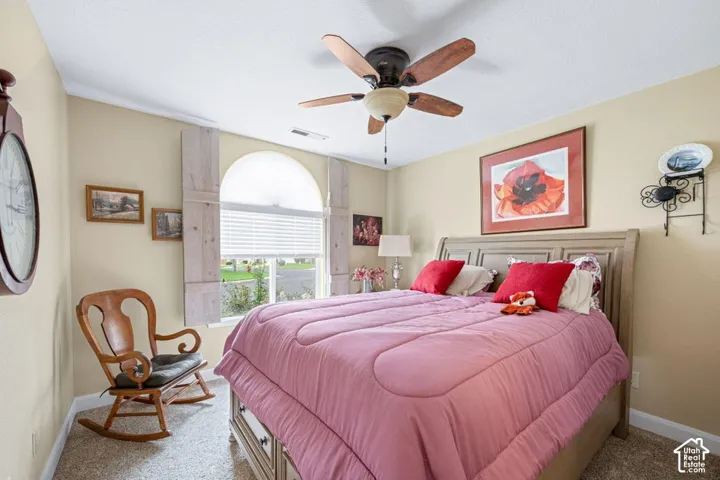 Arched window featuring decorative wooden shutters, neutral wall coloring, and a multi-blade ceiling fan with integrated lighting
