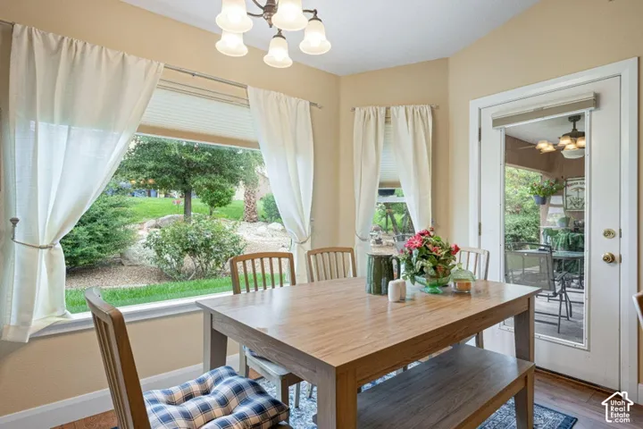 Dining area featuring a bay window, wood-finish flooring, multi-light chandelier, and glass-paneled exterior door