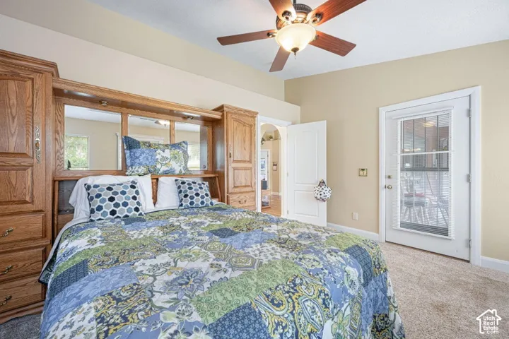 Vaulted ceiling featuring a central lighted ceiling fan, built-in wood cabinetry with integrated mirrored backsplash, and a glass-paneled exterior door